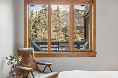 a bedroom with a window with a mountain view at 2BR Modern Luxe Condo with Hot Tub and Views in Canmore