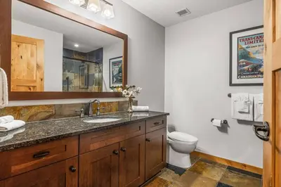 a bathroom with a sink and a toilet and a mirror at 2BR Modern Luxe Condo with Hot Tub and Views in Canmore