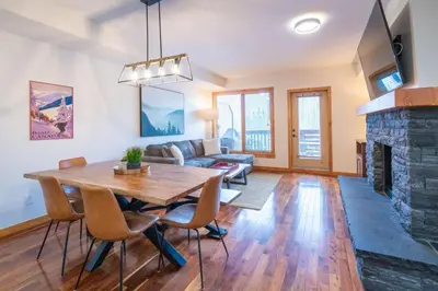 a living room with a table and a fireplace at Serene 3BR Rockies Stay with Hot Tub and Near DT in Canmore