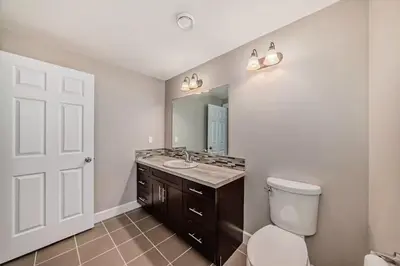 a bathroom with a toilet and a sink and a mirror at Waterfront Home, Fireplace, 90 min to Banff in Airdrie
