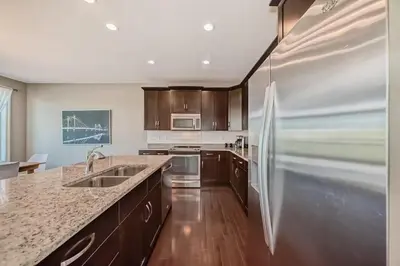 a kitchen with a stainless steel refrigerator and wooden cabinets at Waterfront Home, Fireplace, 90 min to Banff in Airdrie