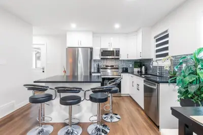 a kitchen with white cabinets and black counter tops at Spacious Home • 3BR • Close to Whyte and Downtown in Edmonton