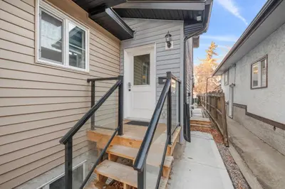 a stairway leading to a white door on a house at Spacious Home • 3BR • Close to Whyte and Downtown in Edmonton