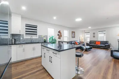 an open kitchen and living room with white cabinets at Spacious Home • 3BR • Close to Whyte and Downtown in Edmonton