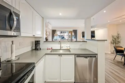 a kitchen with white cabinets and a stainless steel sink at Private Hot Tub | Pool | AC | Free Parking in Whistler