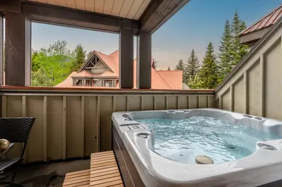 a jacuzzi tub sitting on a porch with a window at Private Hot Tub | Pool | AC | Free Parking in Whistler