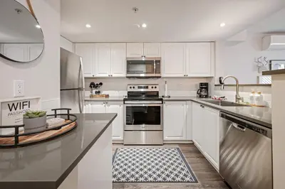 a kitchen with white cabinets and stainless steel appliances at Private Hot Tub | Pool | AC | Free Parking in Whistler