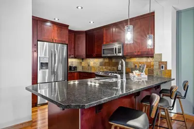 a kitchen with a granite counter top and wooden cabinets at Luxurious Condo Mountain Views Hot-tub and Billiards in Canmore