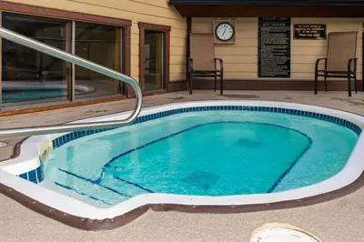 a swimming pool in front of a building with a clock at Luxurious Condo Mountain Views Hot-tub and Billiards in Canmore