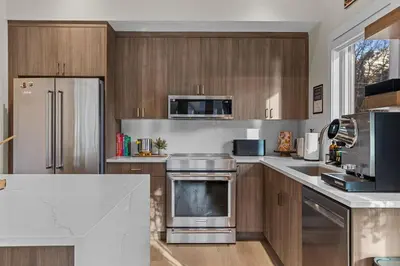 a kitchen with wooden cabinets and stainless steel appliances at Sisters' Solstice Villa by WeekAway Vacations in Canmore