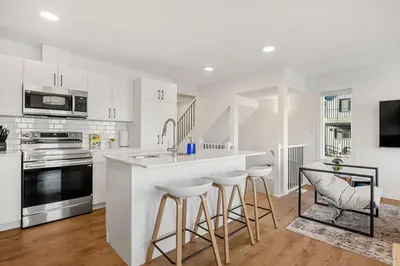 a kitchen with white cabinets and a bar with stools at Luxury Family Retreat with Games, King Bed and Garage in Edmonton