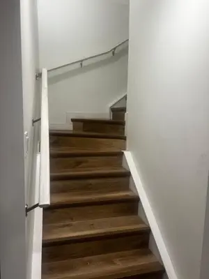 a staircase with wooden floors and white walls at Private room in Basement suite in Edmonton