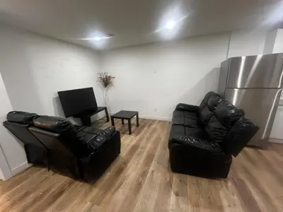 a living room with two leather chairs and a refrigerator at Private room in Basement suite in Edmonton