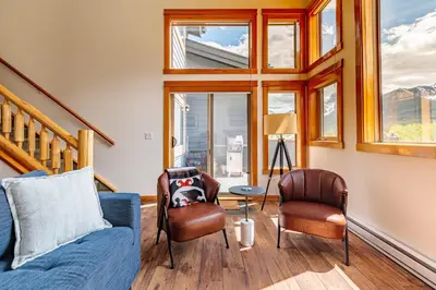 a living room with a blue couch and two chairs at Cloud Nine - Stunning Views Rooftop Hot Tub in Canmore