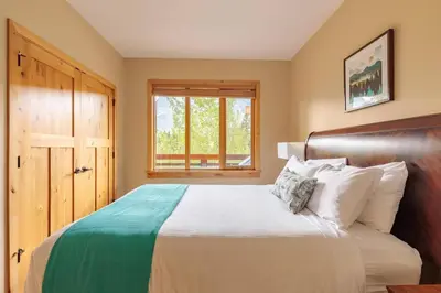 a bedroom with a bed with a wooden headboard and a window at Spring Creek Serenity at Rundle Cliffs Lodge in Canmore