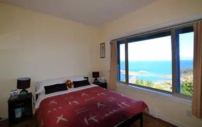 a bedroom with a bed and a large window at Gibralter Rock Ocean View B&B in Nanaimo