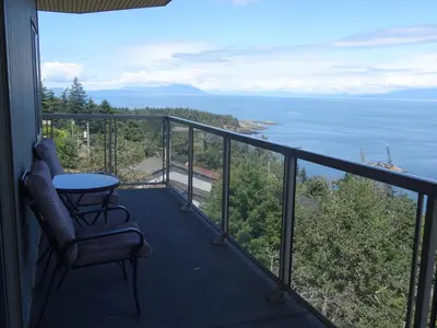 a balcony with a table and a chair and the ocean at Gibralter Rock Ocean View B&B in Nanaimo