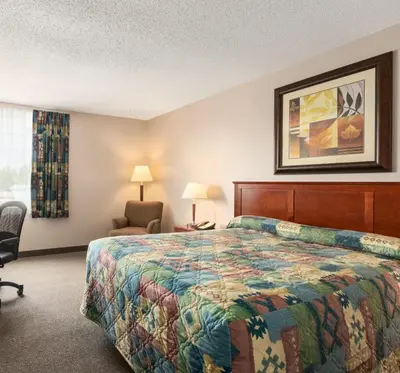 a hotel room with a bed and a chair at Canada Grey Motor Inn in Hanna