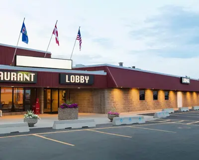 a parking lot in front of a building with flags at Canada Grey Motor Inn in Hanna