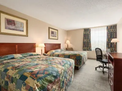 a hotel room with two beds and a desk at Canada Grey Motor Inn in Hanna