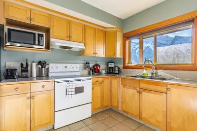 a kitchen with wooden cabinets and a white stove top oven at Valhalla - Pure Mountain Bliss in Canmore