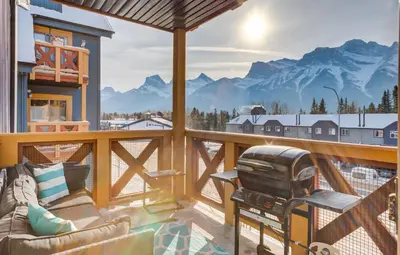 a balcony with a couch and a grill and mountains at Valhalla - Pure Mountain Bliss in Canmore