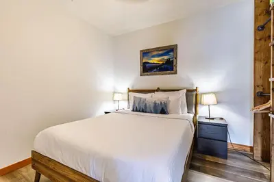a bedroom with a large white bed and two lamps at Valhalla - Pure Mountain Bliss in Canmore