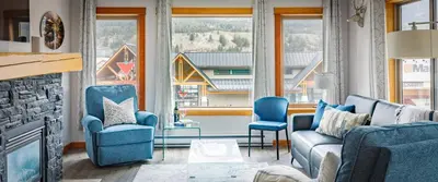 a living room with blue chairs and a fireplace at Alpen Glow at Canmore Crossing in Canmore