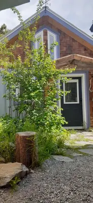 a house with a black door and a tree stump at Yukon Sweet Spot Bed and Bakery in Whitehorse