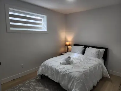 a bedroom with a white bed with a window at Cozy, Classy 2 BedRM Private Suite with Netflix and Parking in Edmonton