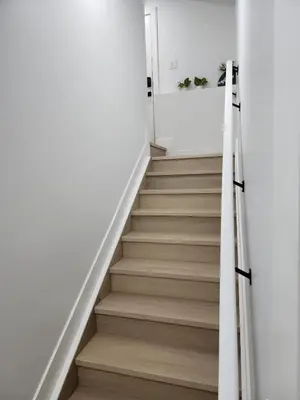 a staircase in a house with white walls and wooden floors at Cozy, Classy 2 BedRM Private Suite with Netflix and Parking in Edmonton