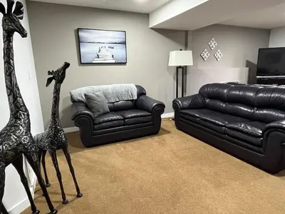 a living room with a black leather couch and giraffe statues at 20 KLM from SilverStar with private Hot Tub in Vernon
