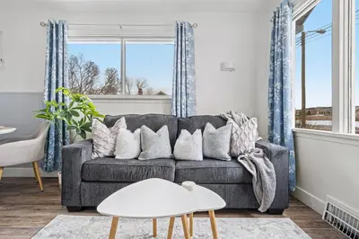 a living room with a gray couch with pillows at Blue Raptor Family-Friendly 3BR Private Yard in Drumheller