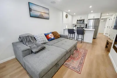 a living room with a couch and a kitchen at Deluxe Mahogany Lake Getaway Sleeps 4 in Calgary