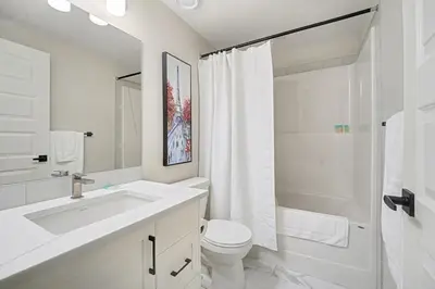 a white bathroom with a sink and a toilet at Deluxe Mahogany Lake Getaway Sleeps 4 in Calgary
