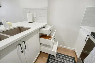 a kitchen with white cabinets and a sink at Deluxe Mahogany Lake Getaway Sleeps 4 in Calgary