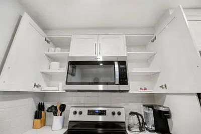 a kitchen with white cabinets and a microwave at Deluxe 2-Bedroom Getaway Near Mahogany Lake in Calgary