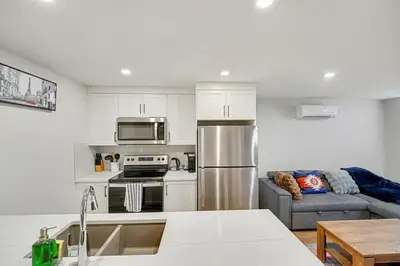 a kitchen with a stainless steel refrigerator and a couch at Deluxe 2-Bedroom Getaway Near Mahogany Lake in Calgary