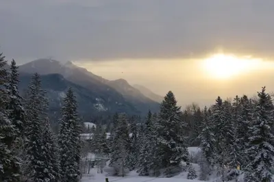 a snow covered mountain with the sun in the distance at Golden Moments in Golden