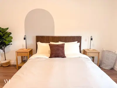 a bedroom with a large white bed with two tables at Oso Skyview Suite - DT modern 2 bed, 2 bath in Golden