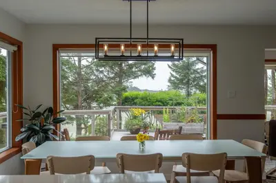 a dining room with a table and chairs and a large window at Chesterman on the Point - Beachfront in Tofino
