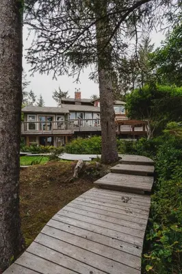 a wooden walkway in front of a large house at Chesterman on the Point - Beachfront in Tofino