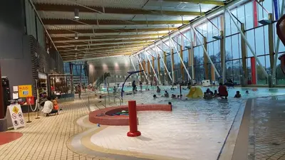 a large indoor swimming pool with people in a building at Sunny 1BR Detached Suite - Near City Center in Vancouver