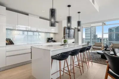 a kitchen with white cabinets and a bar with stools at Manhattan Right Next to Stampede Grounds DT in Calgary