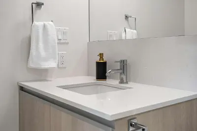 a bathroom with a sink with a soap dispenser on it at Manhattan Right Next to Stampede Grounds DT in Calgary