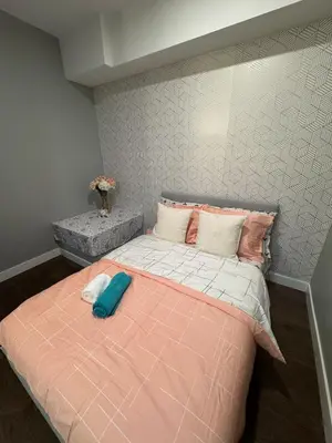 a bedroom with a bed with a pink comforter at Lovely 2 bedroom suite in Langford in Metchosin