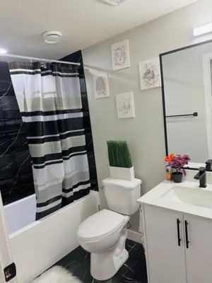 a bathroom with a toilet and a tub and a sink at Roj exclusive comfort home in Edmonton