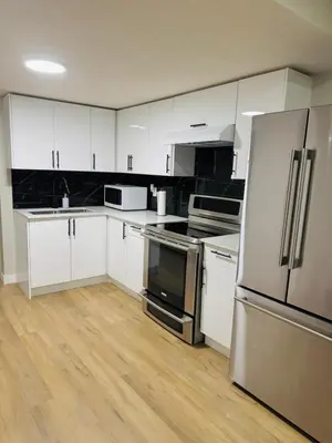 a kitchen with white cabinets and stainless steel appliances at Roj exclusive comfort home in Edmonton