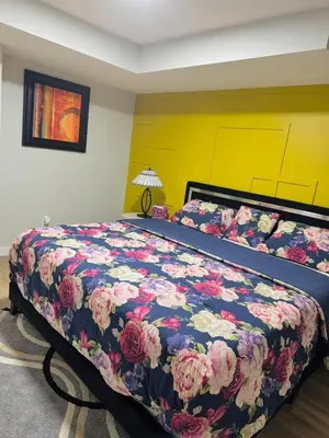 a bedroom with a large bed with a floral bedspread at Roj exclusive comfort home in Edmonton