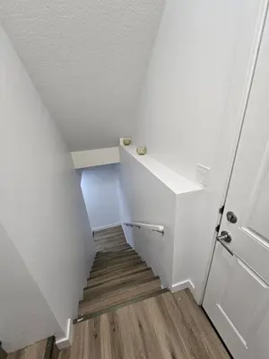 a staircase with white walls and a white door and wooden floors at Clearwater Chestermere in Chestermere